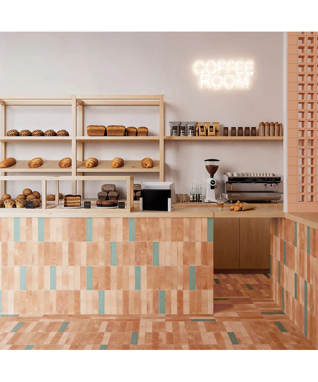 A cozy bakery interior with wooden shelves displaying assorted breads and pastries, a tiled counter in warm peach and teal tones, a coffee grinder, espresso machine, and a glowing 'COFFEE ROOM' neon sign on the wall.