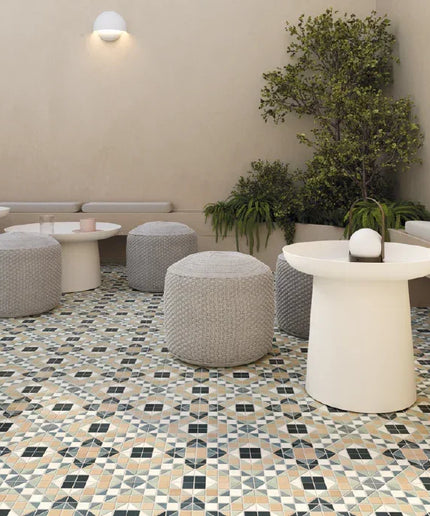 Modern indoor setting with patterned floor, white tables, gray ottomans, and green plants.