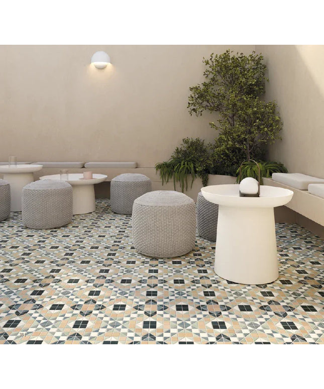 Modern indoor setting with patterned floor, white tables, gray ottomans, and green plants.