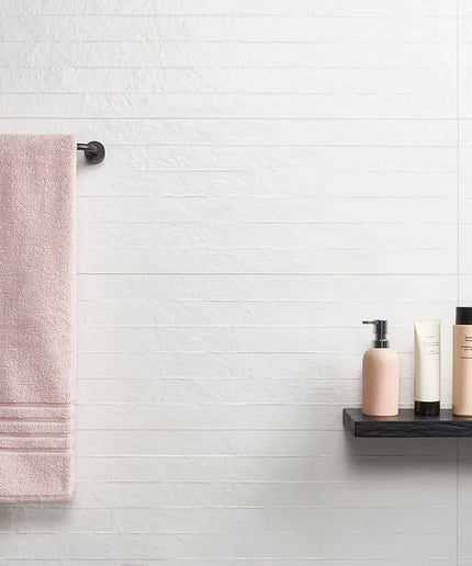 Bathroom setting with a towel hanging on a rack and skincare products on a shelf.