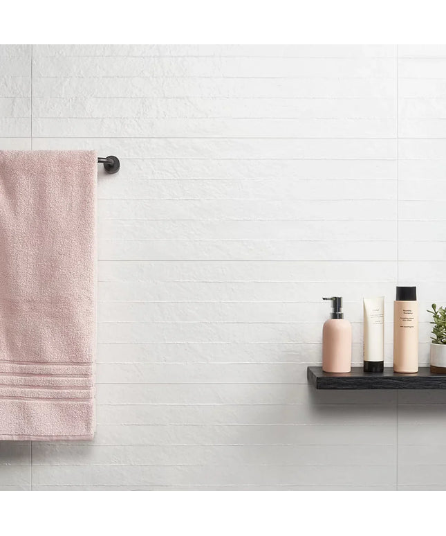Bathroom setting with a towel hanging on a rack and skincare products on a shelf.