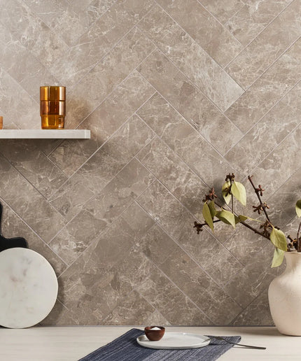 Taupe marble-look tiles in a herringbone pattern used on a modern kitchen backsplash.