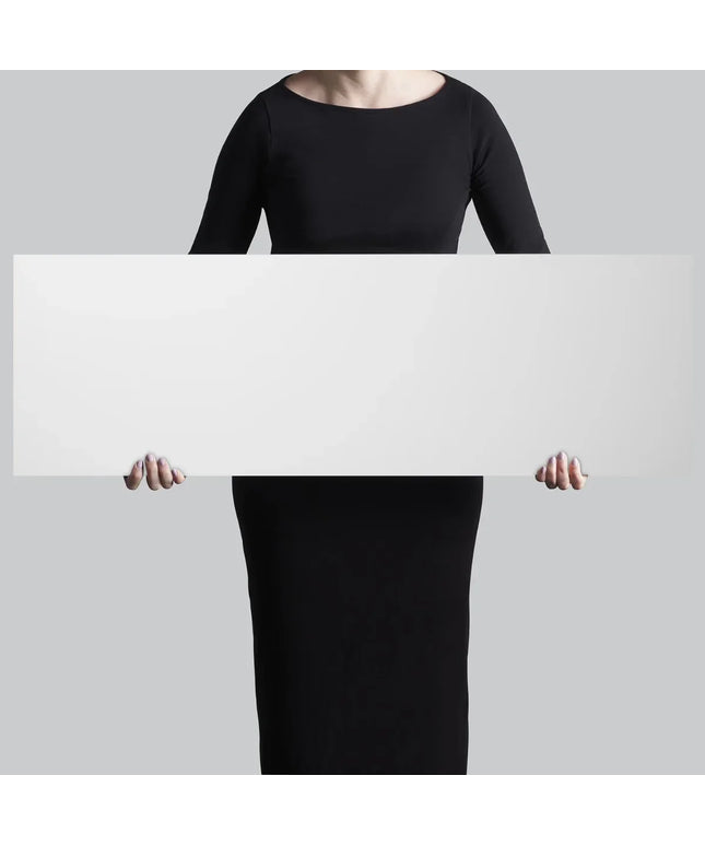 Person wearing a black dress holding a white rectangular board against a gray background