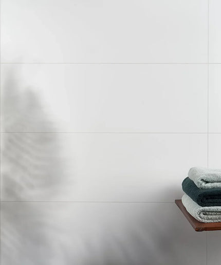 Stack of towels on a wooden shelf against a tiled wall