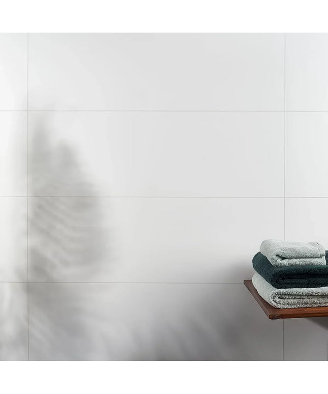 Stack of towels on a wooden shelf against a tiled wall