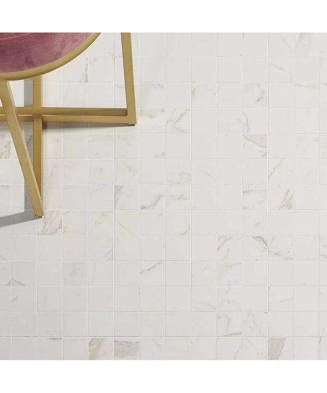 Calacatta marble-look 2x2 floor tile with subtle veining and a gold frame chair
