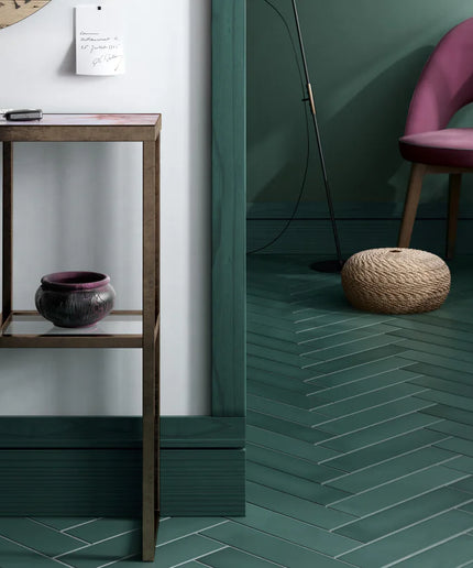 Modern interior with a pink chair, wooden table, and green tiled floor.