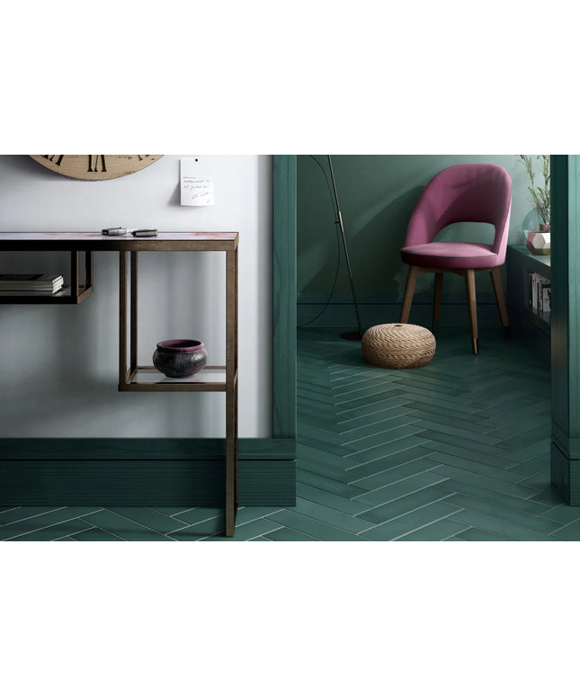 Modern interior with a pink chair, wooden table, and green tiled floor.