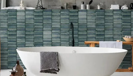 Bathroom with a white freestanding bathtub against a tiled wall. karatsu tile
