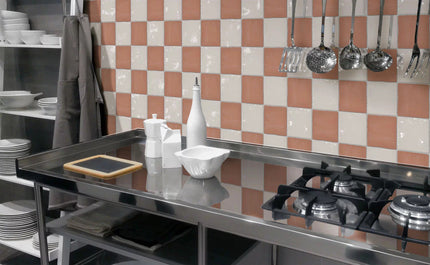 Modern kitchen backsplash with glossy checkerboard pink and white tiles, stainless stove.