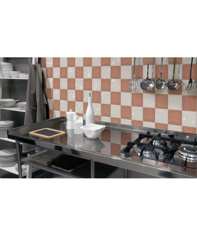 Modern kitchen backsplash with glossy checkerboard pink and white tiles, stainless stove.