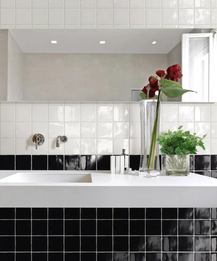 Modern bathroom with glossy black and white square tiles, white sink, and glass vases