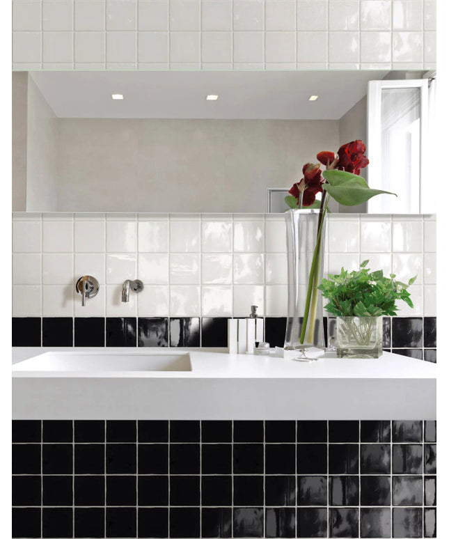 Modern bathroom with glossy black and white square tiles, white sink, and glass vases