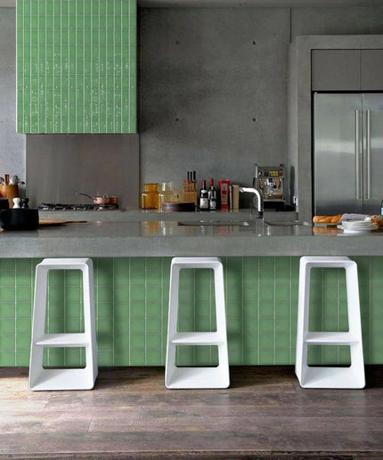 Modern kitchen with green tile backsplash and peninsula, white bar stools, and stainless steel appliances