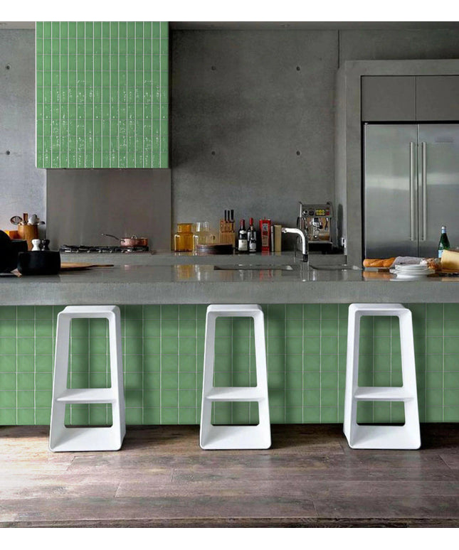 Modern kitchen with green tile backsplash and peninsula, white bar stools, and stainless steel appliances