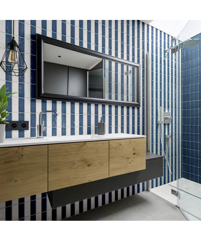 Modern bathroom with blue and white vertical wall tiles, wood vanity, and glass shower