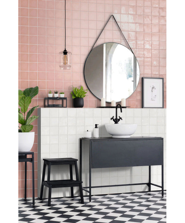 Modern bathroom with pink and white square tile backsplash, black vanity, and round mirror