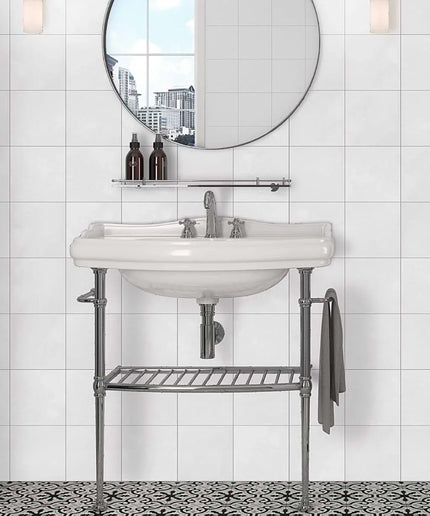 Bathroom vanity with round mirror and decorative elements against a tiled wall.