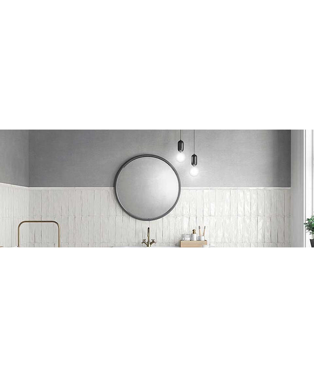 Round mirror on a gray wall with white tiled walls and a sink.
