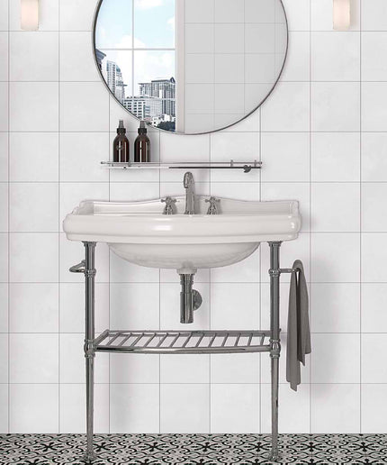 Bathroom vanity with round mirror and decorative elements against a tiled wall.
