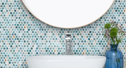 Bathroom with blue mosaic tiles, white sink, and round mirror.