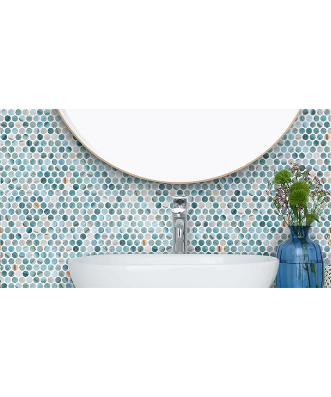 Blue and white round mosaic tile backsplash behind a bathroom sink with a mirror and vase