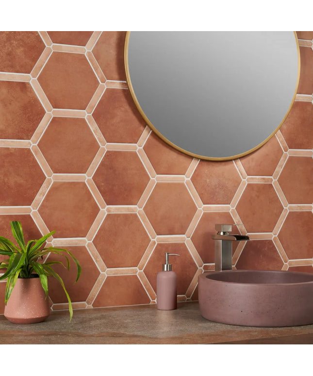 Bathroom with terracotta hexagonal tiles, a round mirror, and a sink.